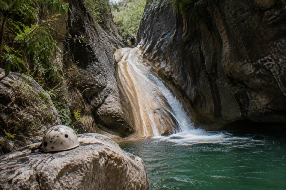 Smooth water-carved rock chute between canyon walls with a pool at the bottom